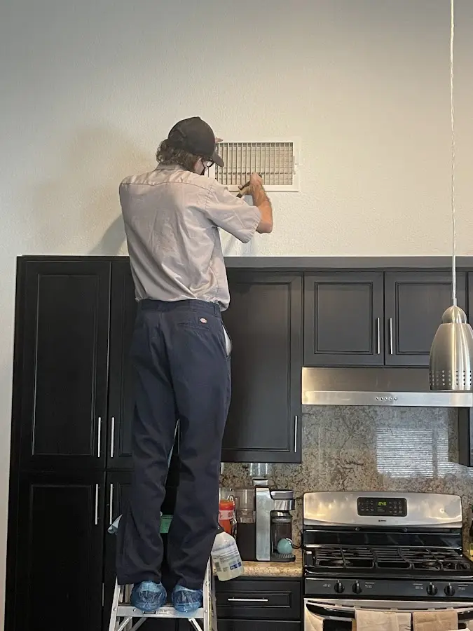 Technician inspecting an air vent during HVAC service in Pine Bluff
